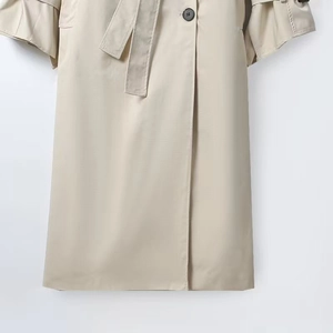 Detail of beige trench coat with textured fabric, waist belt and classic black button