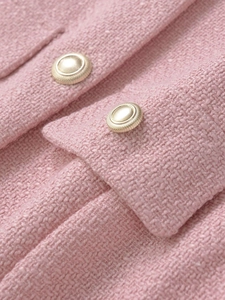 Close-up of pink tweed vest fabric texture with detailed golden embossed buttons
