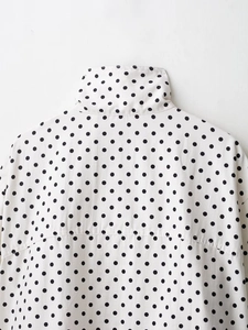 Detail shot of black polka dot pattern on white seersucker fabric and collar construction