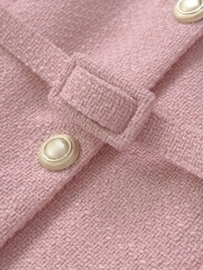 Close-up of pink tweed vest fabric texture with detailed metallic buttons and woven pattern
