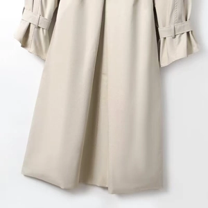 Detailed close-up of khaki trench coat hem and sleeves with decorative buckle strap design