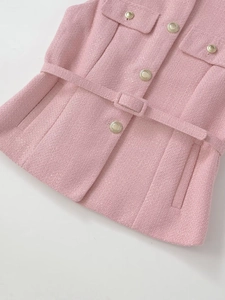 Detail of pink tweed vest showing gold buttons and waist belt with fabric texture
