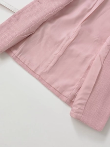 Detailed close-up of pink tweed jacket fabric and smooth satin lining texture