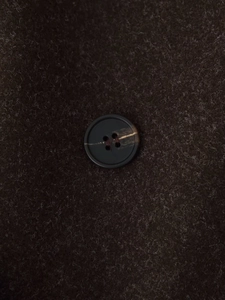 Detailed macro view of dark brown wool fabric and elegant marble-textured button