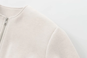 Detail of round neckline and silver zipper on a beige wool blend baseball jacket