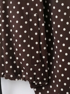 Detail der braunen Polka-Dot-Jacke mit Taschennähten und elastischem Raffsaum