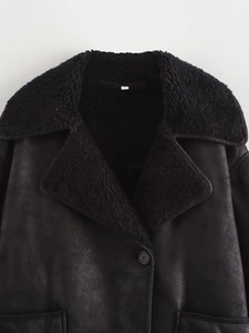 Detail of black faux suede jacket featuring warm shearling lapel and flap pocket design