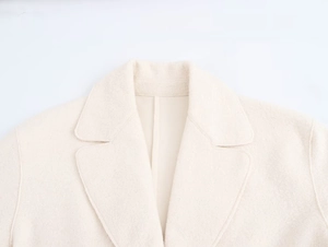 Detail of classic notched lapel and fine wool texture on oversized cream overcoat