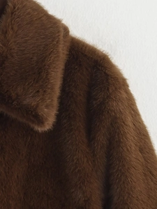 Detailed close-up of thick dark brown faux fur collar and texture on the fashion coat