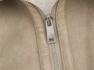 Close-up of metal zipper and white faux shearling lining on khaki suede jacket