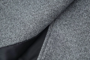 Close-up of grey wool blend fabric texture with black lining on a short coat