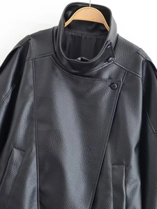 Close-up of black biker jacket featuring textured faux leather and asymmetric buttons