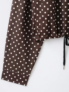 Detail der braun gepunkteten Jacke mit schwarzem Kordelzug und verstellbarem Knopf am Ärmel