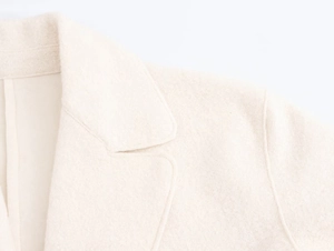 Detailed close-up of notched lapels and wool blend texture on minimalist oatmeal coat