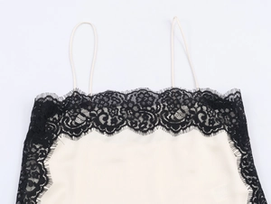 Close-up of cream satin top featuring delicate black eyelash lace trim and thin straps