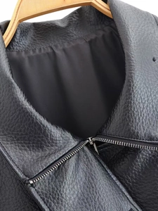 Close-up of black faux leather jacket showing lychee texture and diagonal metal zipper