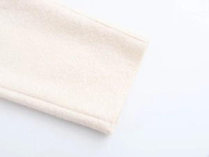 Close-up of beige textured wool fabric showing the premium stitching on garment edge