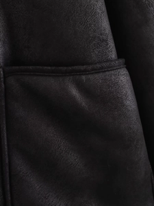 Macro shot of black faux leather baseball jacket featuring detailed horizontal stitching