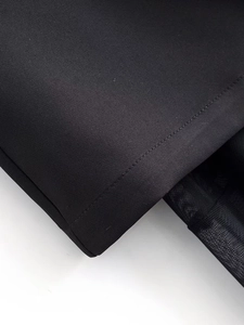 Detailed close-up of the black dress fabric with fine mesh trim and precise stitching