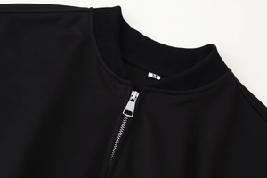 Détail de la fermeture éclair en métal et col côtelé sur veste bomber noire
