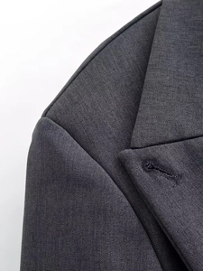 Macro detail of charcoal grey double-breasted suit lapel showing fine twill fabric texture