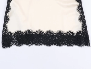 Detail of beige silk satin fabric with fine black eyelash lace trim and scalloped edges