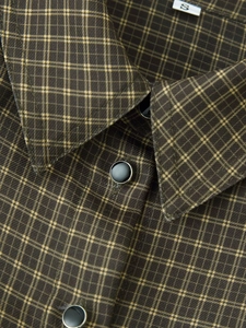 Macro shot of dark plaid shirt collar with black buttons and fine fabric texture detail