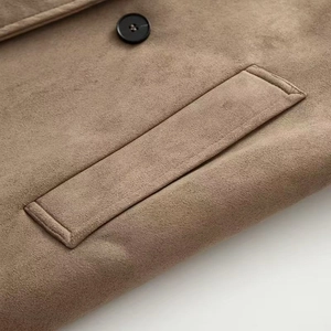 Dettaglio ravvicinato di un trench color cammello scuro con trama scamosciata e bottone