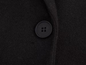 Macro shot of circular four-hole buttons on a black wool coat featuring premium matte texture