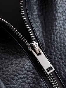 Detailed close-up of a silver metal zipper on premium black lychee texture leather jacket