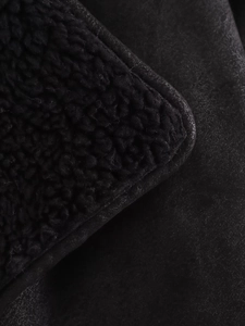 Detail of premium black faux shearling lining and matte suede texture on the baseball jacket