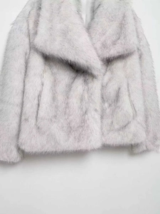 Détail de la texture luxueuse d'un manteau en fausse fourrure gris argenté dégradé