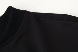 Détail du col côtelé et des coutures sur un ensemble de sport veste pilote noir