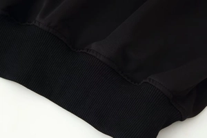 Détail du bord-côte et de la double couture sur l'ourlet d'une veste noire