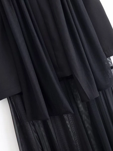 Detailed close-up of pleated black fabric and layered sheer mesh on the dress