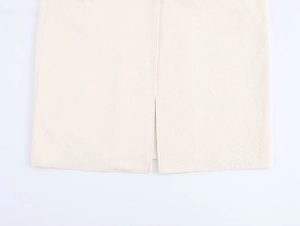 Detail of a minimalist off-white wool coat hem featuring a neat center back slit