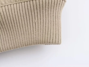Detail view of khaki ribbed knit cuffs and collar texture on a faux fur jacket