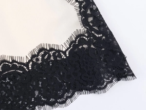 Detailed close-up of intricate black floral eyelash lace trim on satin fabric