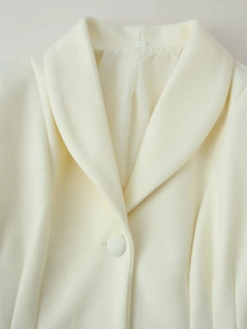 Close-up of cream white wool coat featuring shawl collar and matching fabric button detail