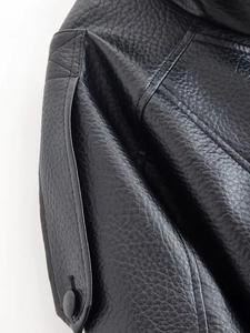 Close-up of black faux leather jacket showing lychee texture and stitched button details