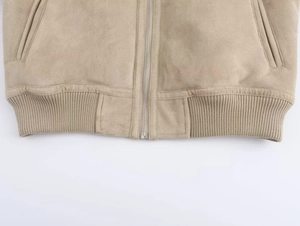Detail view of khaki suede jacket featuring metal zipper and ribbed hem texture