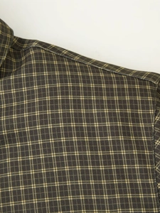 Close-up of shoulder seam and weave texture on the olive green plaid shirt jacket