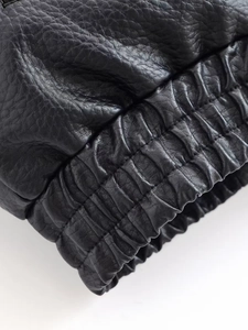 Detail shot of black faux leather jacket showing elastic cuff and textured lychee grain
