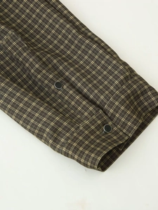Detail shot of plaid shirt cuffs with dual black buttons and classic brown check pattern
