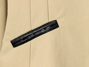 Gros plan détaillé sur tissu sergé beige avec bordure en cuir noir et coutures précises