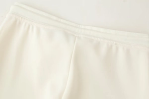 Détail de la taille élastique crème avec coutures renforcées sur un pantalon lisse