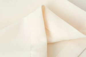 Gros plan sur la texture du tissu tissé beige et les coutures de la veste de sport