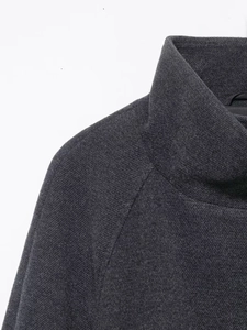 Detailed close-up of dark grey high neck coat with raglan sleeves and fine knit texture