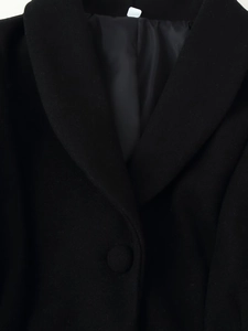 Detailed view of classic notch lapels and fabric button on a black wool coat for women