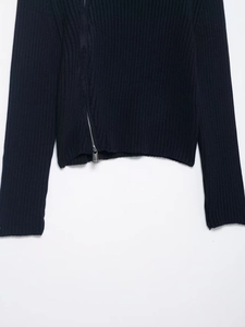 Detailed close-up of dark blue ribbed knit fabric featuring a silver diagonal metal zipper